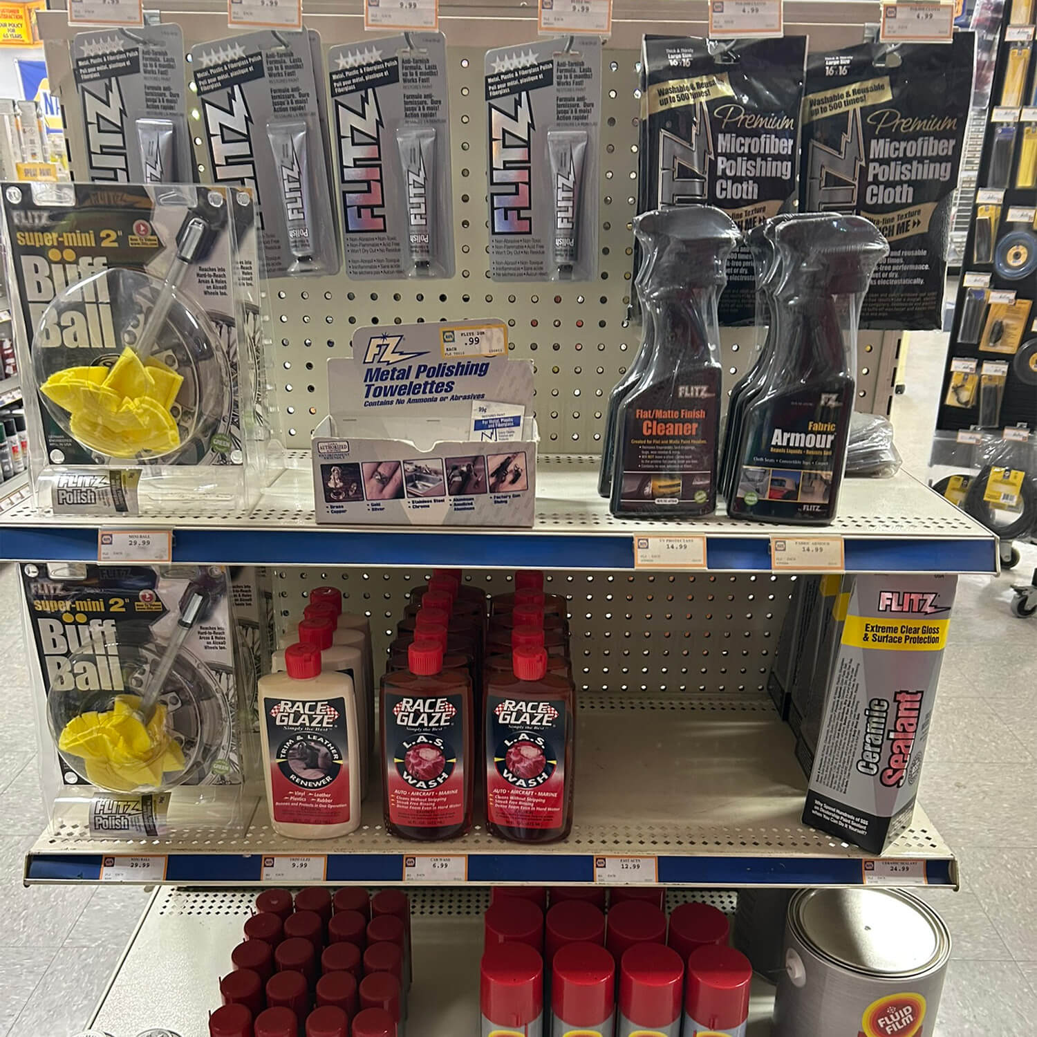 Flitz polishes and Race Glaze bottles with pressure-sensitive labels on a retail endcap