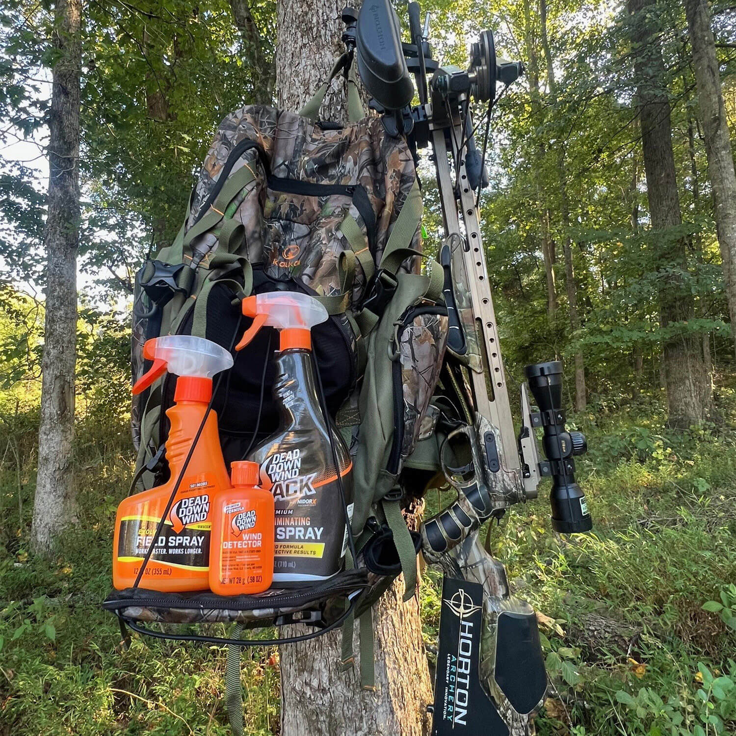 Dead Down Wind field spray bottles with full-body shrink sleeves on a hunting pack in the woods