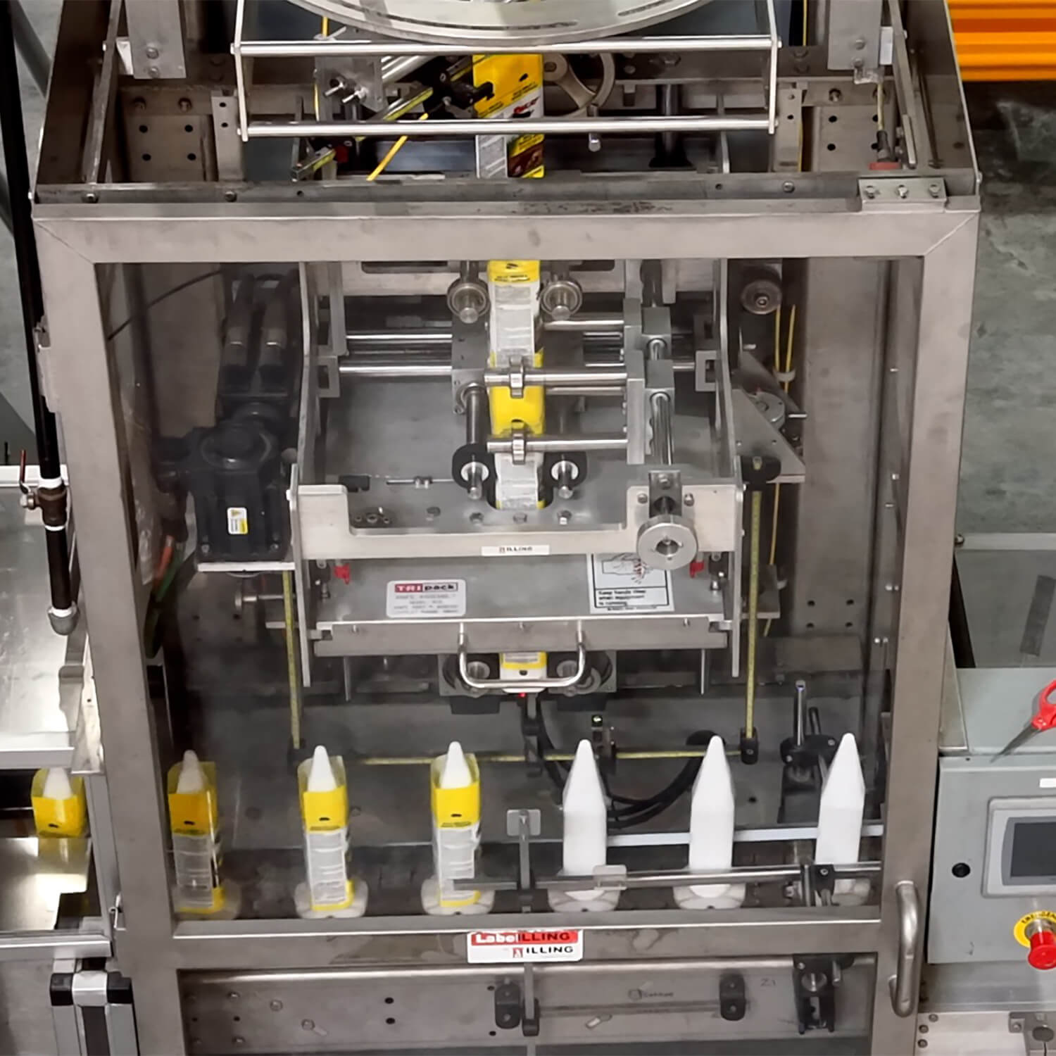 White bottles receiving yellow shrink sleeves on an ILLING sleeve applicator