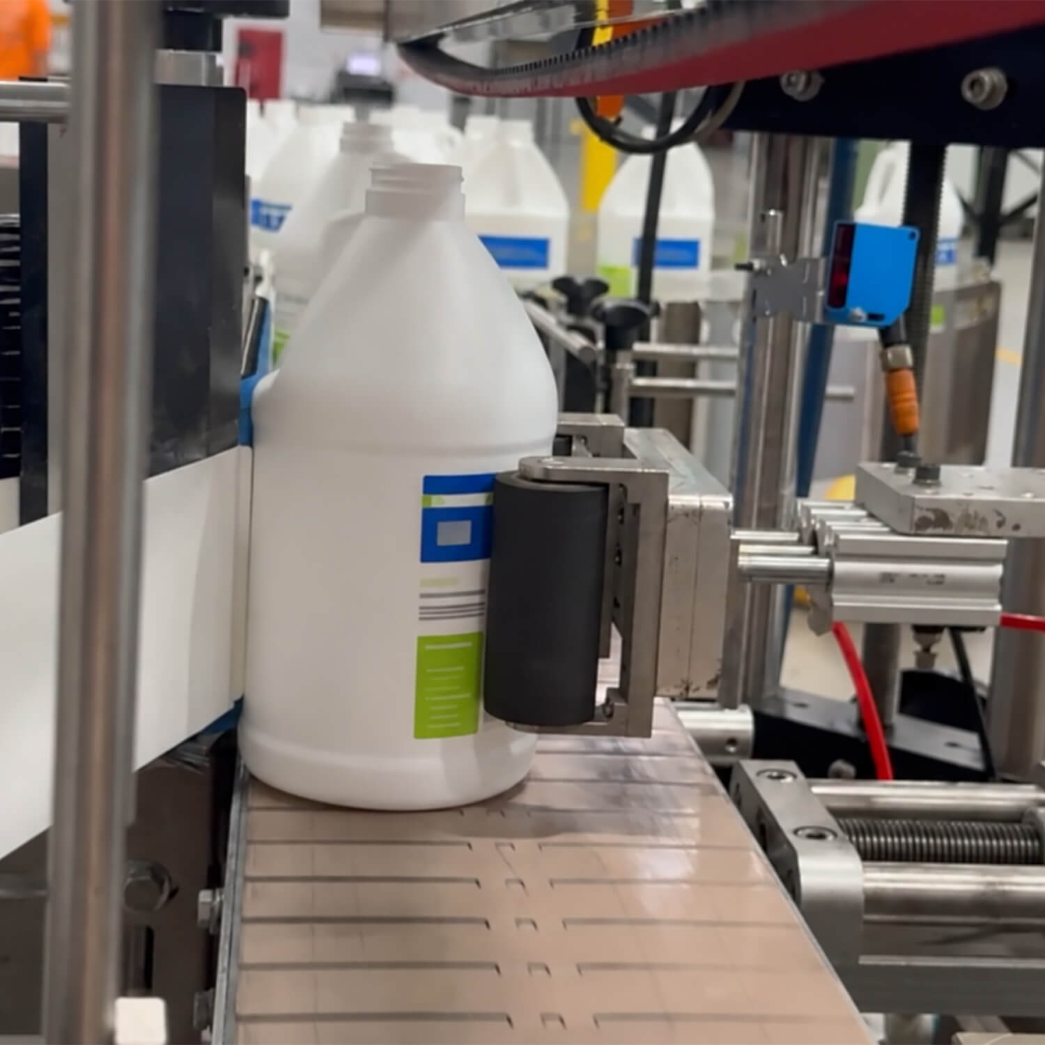 A gallon jug receiving a pressure-sensitive label on an ILLING labeling line