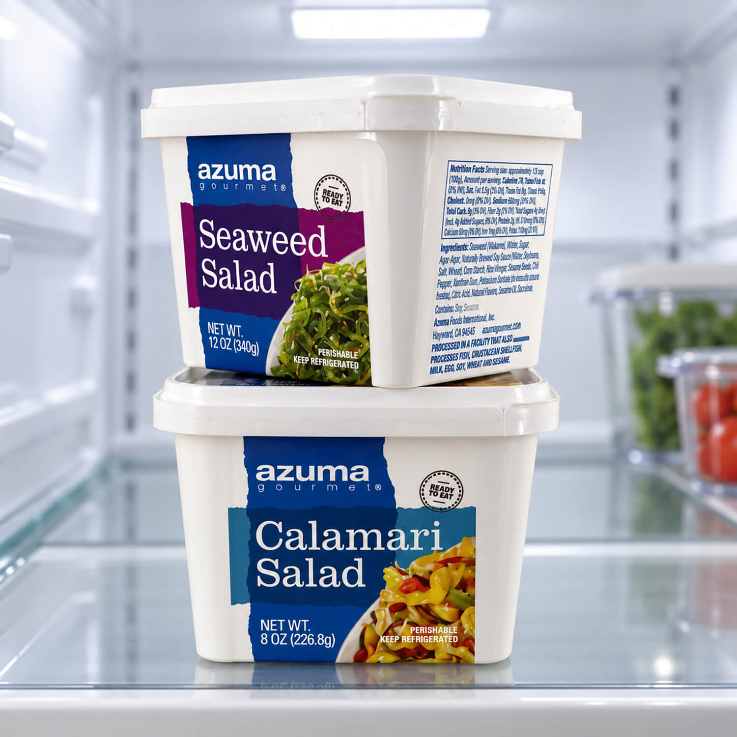 Two stacked Azuma Gourmet salad tubs with labels on a refrigerator shelf