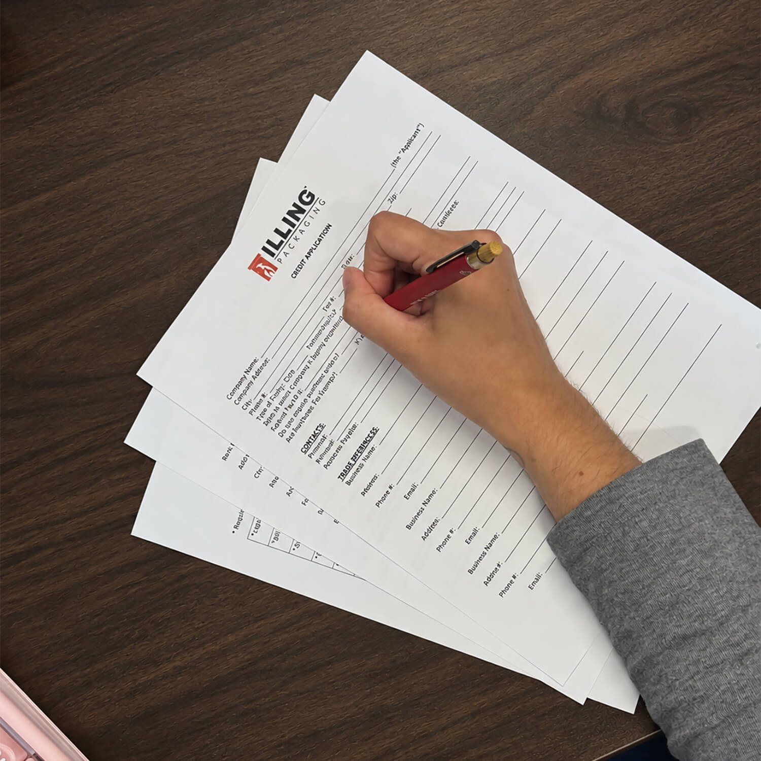 A person filling out an ILLING Packaging credit application form